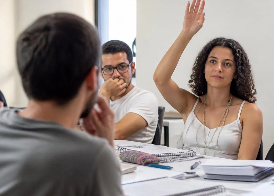 Dupla preparando a rodada seguinte, com caderno aberto e canetas coloridas na mesa